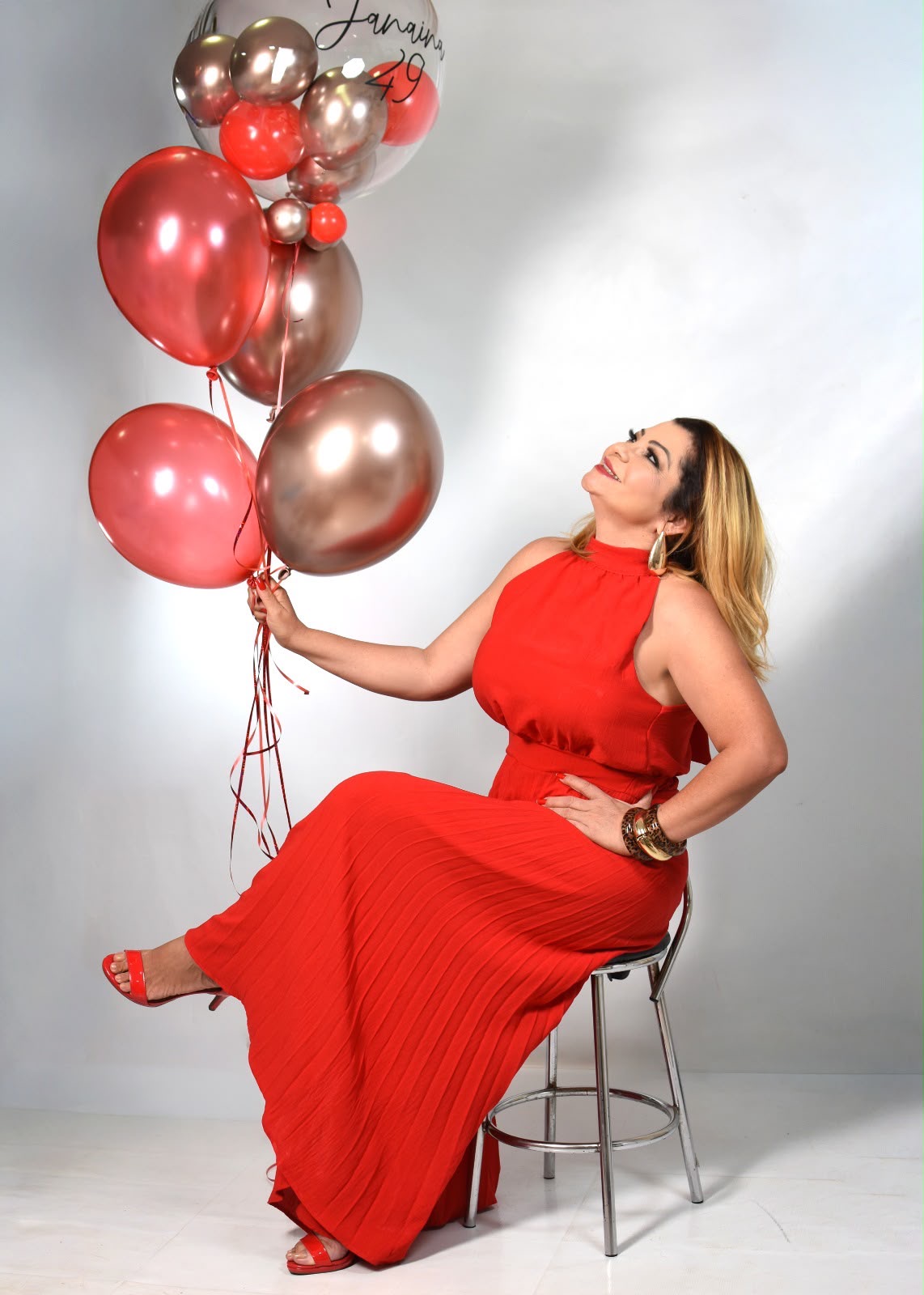Janaina de vestido vermelho segurando balões